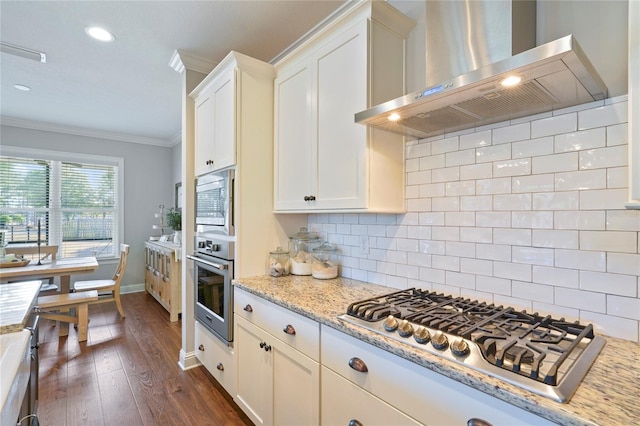 636 Meadow Lake Dr, Freeport, FL 32439 - kitchen with wall chimney exhaust hood, stainless steel appliances, ornamental molding, dark wood finished floors, and white cabinetry