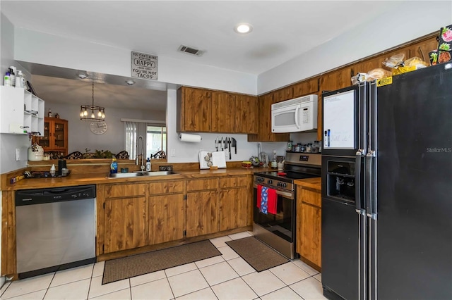 616 Bryan Terrace Dr, Brandon, FL 33511 - kitchen with appliances with stainless steel finishes, brown cabinetry, a chandelier, light tile patterned floors, and dark countertops