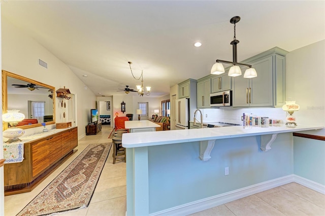 133 Tucker Ave, Sarasota, FL 34232 - kitchen with light countertops, a peninsula, a chandelier, freestanding refrigerator, and a breakfast bar