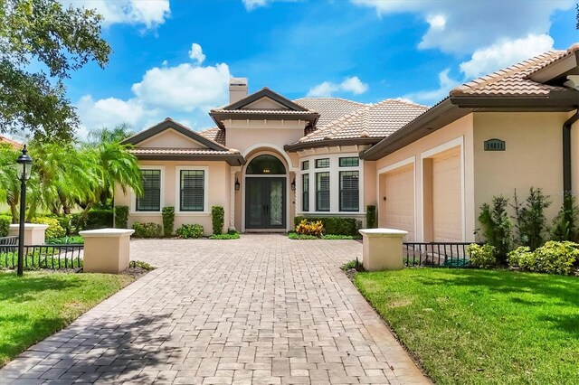 14611 Leopard Creek Pl, Lakewood Ranch, FL 34202 - mediterranean / spanish home featuring a garage, decorative driveway, stucco siding, a tile roof, and a chimney
