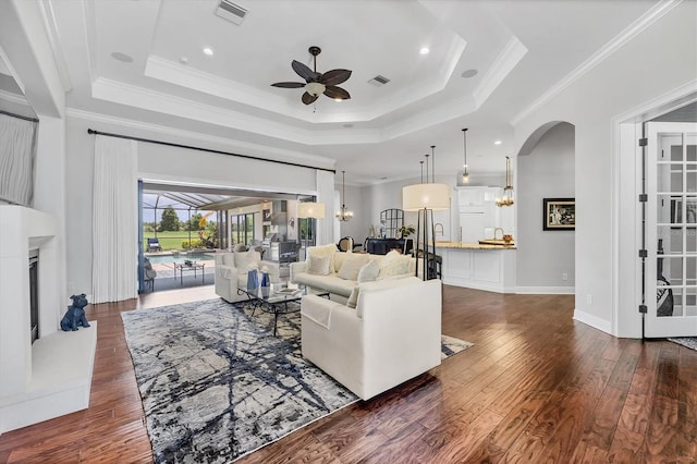 14611 Leopard Creek Pl, Lakewood Ranch, FL 34202 - living area with ceiling fan, arched walkways, a tray ceiling, dark wood finished floors, and crown molding