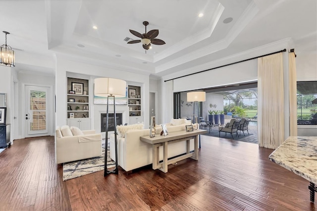 14611 Leopard Creek Pl, Lakewood Ranch, FL 34202 - living area featuring ornamental molding, a ceiling fan, a tray ceiling, dark wood-style flooring, and built in shelves