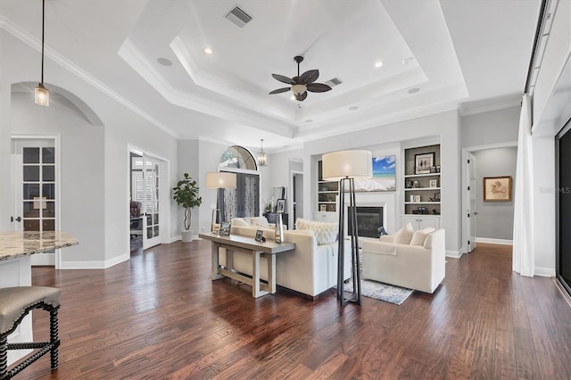 14611 Leopard Creek Pl, Lakewood Ranch, FL 34202 - living area with a raised ceiling, ceiling fan, dark wood-style flooring, a glass covered fireplace, and crown molding