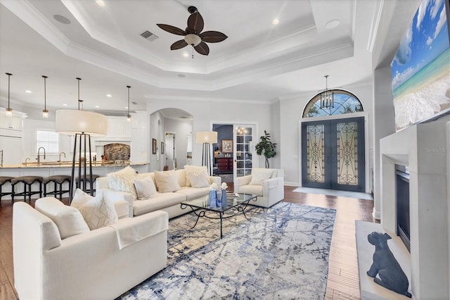 14611 Leopard Creek Pl, Lakewood Ranch, FL 34202 - living room with a ceiling fan, arched walkways, a raised ceiling, wood finished floors, and ornamental molding