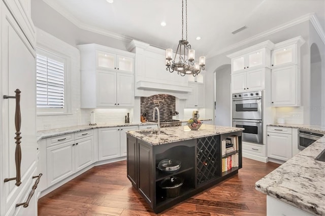 14611 Leopard Creek Pl, Lakewood Ranch, FL 34202 - kitchen with stainless steel double oven, open shelves, arched walkways, crown molding, and white cabinetry