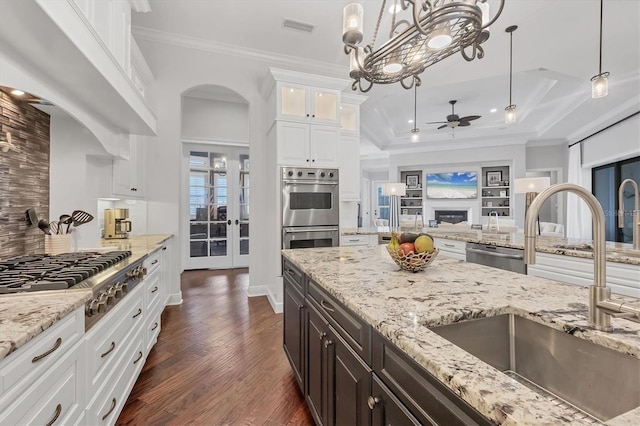 14611 Leopard Creek Pl, Lakewood Ranch, FL 34202 - kitchen featuring stainless steel appliances, a ceiling fan, white cabinets, decorative backsplash, and glass insert cabinets