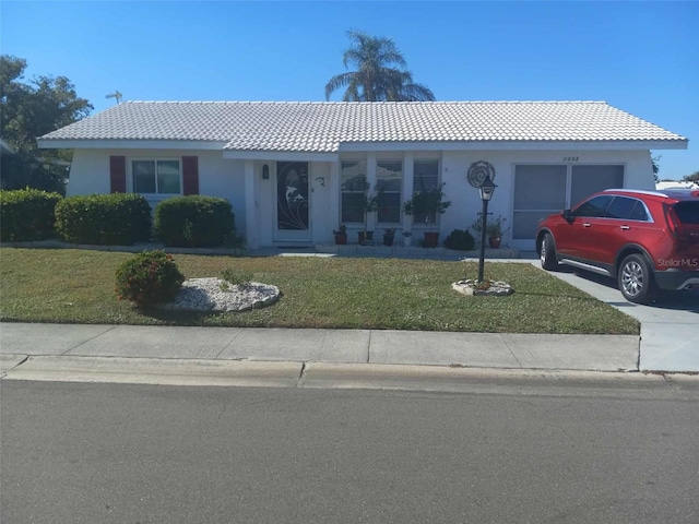 1002 Oakleaf Blvd, Bradenton, FL 34208 - ranch-style house featuring a front lawn, a tile roof, stucco siding, and a garage