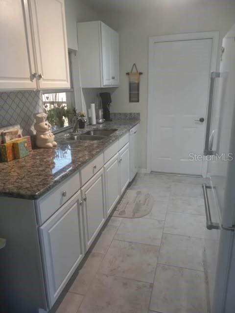 1002 Oakleaf Blvd, Bradenton, FL 34208 - kitchen featuring white appliances, white cabinetry, decorative backsplash, and stone counters