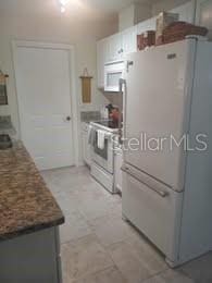 1002 Oakleaf Blvd, Bradenton, FL 34208 - kitchen featuring white appliances, light flooring, and white cabinetry