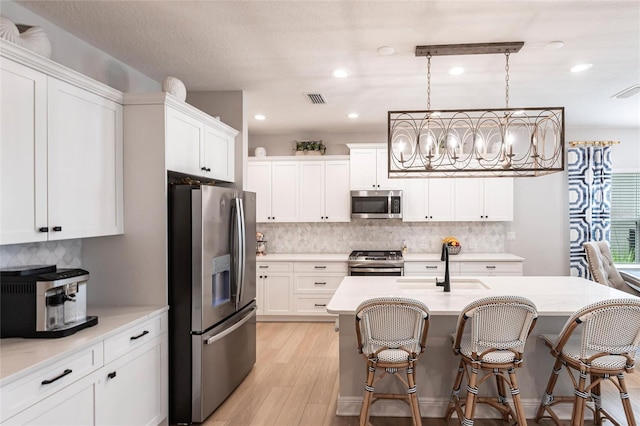 4316 Rustling Pines Ter, Parrish, FL 34219 - kitchen with appliances with stainless steel finishes, light wood-style flooring, backsplash, a breakfast bar area, and white cabinetry