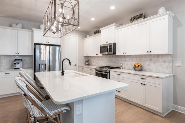 4316 Rustling Pines Ter, Parrish, FL 34219 - kitchen featuring appliances with stainless steel finishes, backsplash, light wood-style floors, a center island with sink, and recessed lighting