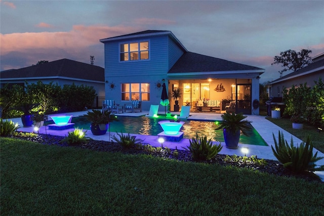 4316 Rustling Pines Ter, Parrish, FL 34219 - back of house at dusk with a patio area, a lawn, an outdoor pool, and roof with shingles