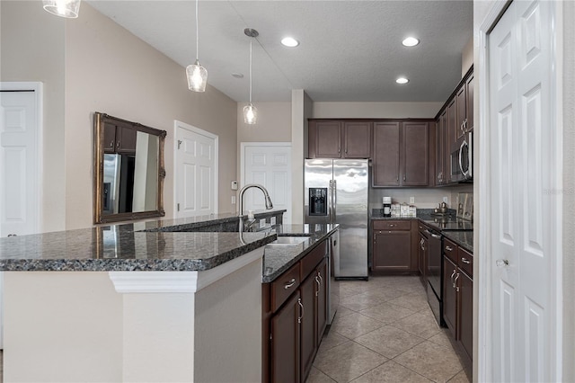 11558 84th Street Cir E Unit 106, Parrish, FL 34219 - kitchen featuring stainless steel appliances, dark brown cabinetry, a center island with sink, light tile patterned flooring, and hanging light fixtures