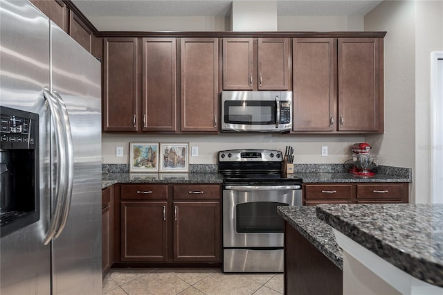 11558 84th Street Cir E Unit 106, Parrish, FL 34219 - kitchen featuring appliances with stainless steel finishes, dark stone counters, light tile patterned floors, dark brown cabinetry, and a textured ceiling