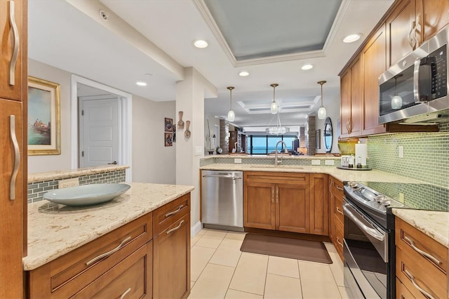 840 The Esplanade N Unit 805, Venice, FL 34285 - kitchen featuring stainless steel appliances, decorative backsplash, brown cabinets, a tray ceiling, and recessed lighting