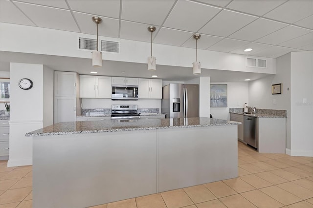 840 The Esplanade N Unit 805, Venice, FL 34285 - kitchen featuring stainless steel appliances, light tile patterned floors, white cabinetry, light stone counters, and a paneled ceiling