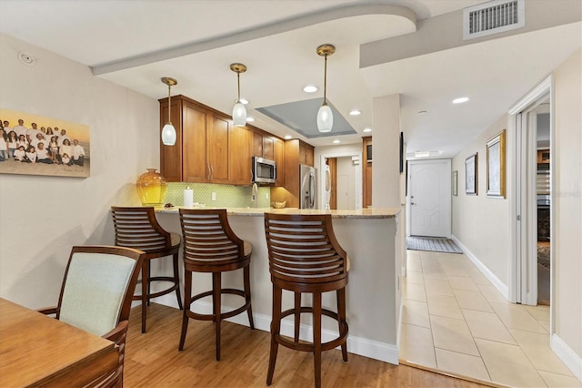 840 The Esplanade N Unit 805, Venice, FL 34285 - kitchen featuring stainless steel appliances, a peninsula, backsplash, brown cabinetry, and recessed lighting