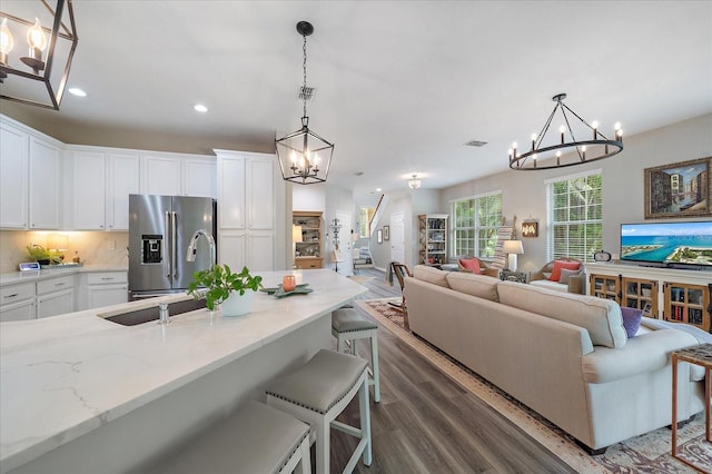 5427 Napa Dr, Sarasota, FL 34243 - kitchen featuring a chandelier, high end refrigerator, dark wood finished floors, open floor plan, and white cabinets