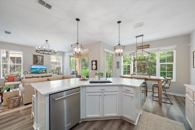 5427 Napa Dr, Sarasota, FL 34243 - kitchen with stainless steel dishwasher, wood finished floors, a kitchen island with sink, white cabinets, and healthy amount of natural light