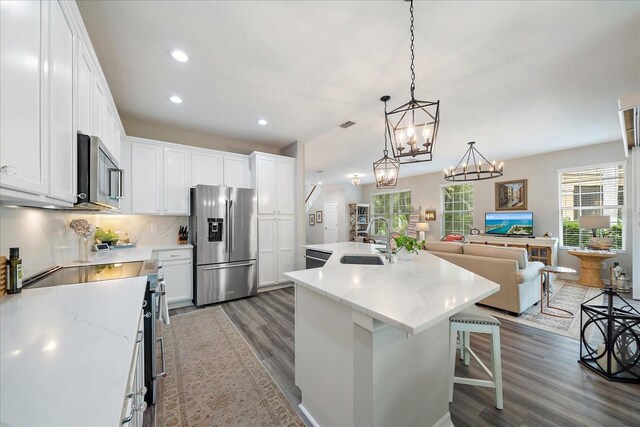 5427 Napa Dr, Sarasota, FL 34243 - kitchen featuring appliances with stainless steel finishes, wood finished floors, recessed lighting, a center island with sink, and white cabinetry