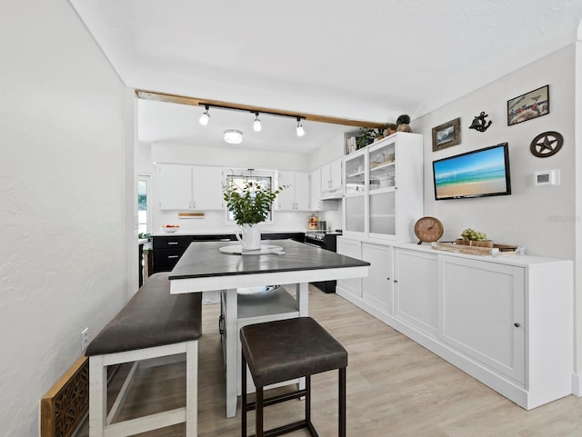 3439 Fair Oaks Pl, Sarasota, FL 34239 - kitchen featuring white cabinetry, light wood finished floors, glass insert cabinets, light countertops, and a kitchen bar