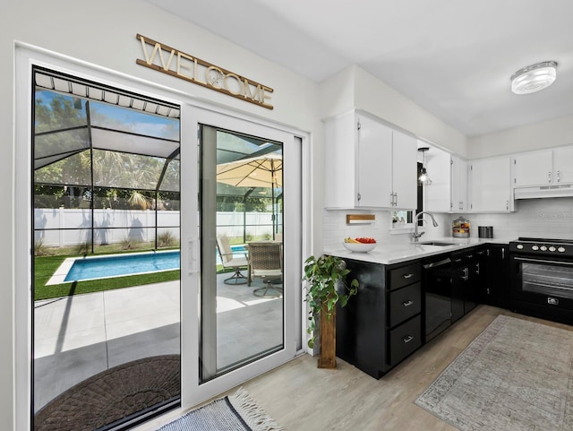 3439 Fair Oaks Pl, Sarasota, FL 34239 - kitchen featuring range, black dishwasher, white cabinets, under cabinet range hood, and light countertops