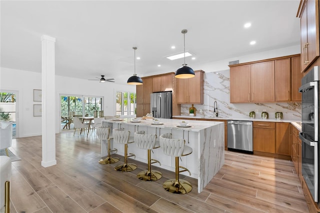 4879 Commonwealth Dr, Sarasota, FL 34242 - kitchen featuring stainless steel appliances, a center island, recessed lighting, decorative backsplash, and light wood-style floors