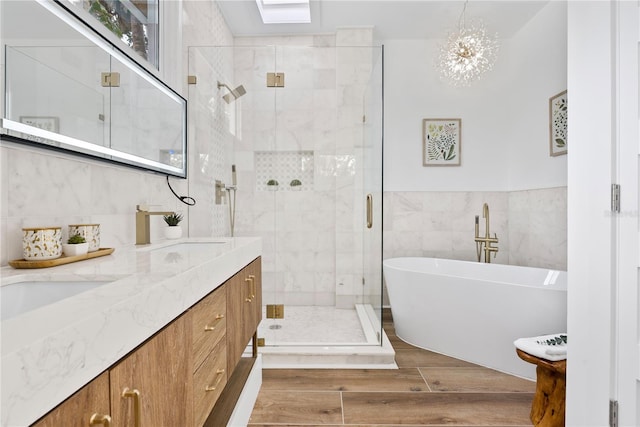 4879 Commonwealth Dr, Sarasota, FL 34242 - bathroom with double vanity, a freestanding tub, a shower stall, wood finished floors, and tile walls