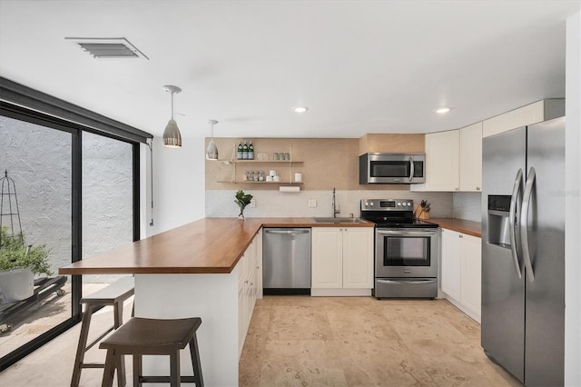 4116 61st Avenue Terrace W, Bradenton, FL 34210 - kitchen featuring stainless steel appliances, a peninsula, wood counters, decorative backsplash, and recessed lighting