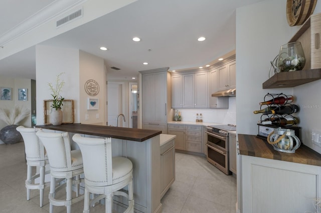 130 Riviera Dunes Way Unit 601, Palmetto, FL 34221 - kitchen featuring a breakfast bar area, double oven range, backsplash, a peninsula, and light tile patterned floors