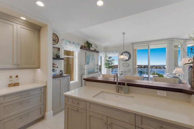130 Riviera Dunes Way Unit 601, Palmetto, FL 34221 - kitchen featuring hanging light fixtures, light countertops, crown molding, backsplash, and light tile patterned floors