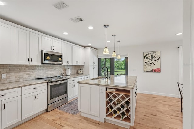 5283 Everwood Run, Sarasota, FL 34235 - kitchen with appliances with stainless steel finishes, light wood-style flooring, backsplash, white cabinetry, and recessed lighting
