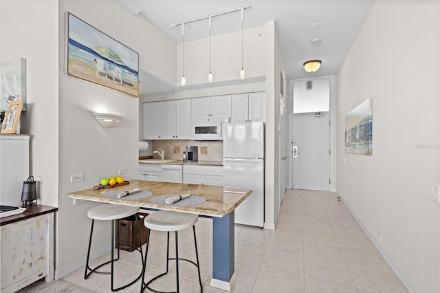 225 Sands Point Rd Unit 6103, Longboat Key, FL 34228 - kitchen with white appliances, rail lighting, a kitchen breakfast bar, white cabinets, and light tile patterned floors
