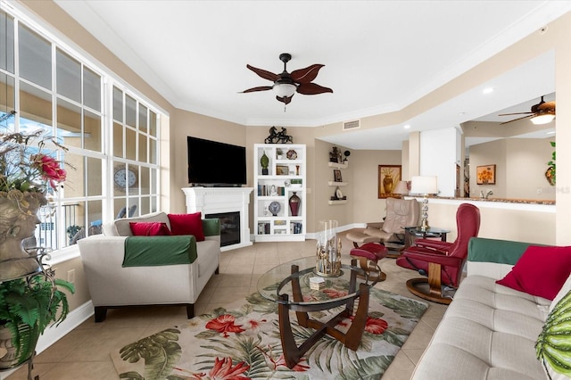 14041 Bellagio Way Unit 414, Osprey, FL 34229 - living room featuring ceiling fan, light tile patterned floors, a glass covered fireplace, and ornamental molding
