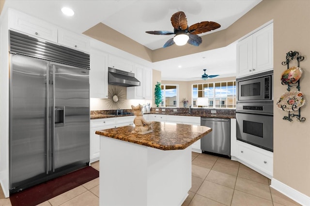 14041 Bellagio Way Unit 414, Osprey, FL 34229 - kitchen featuring built in appliances, under cabinet range hood, a ceiling fan, light tile patterned floors, and white cabinetry