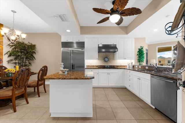 14041 Bellagio Way Unit 414, Osprey, FL 34229 - kitchen with stainless steel appliances, under cabinet range hood, ceiling fan, white cabinetry, and dark stone counters