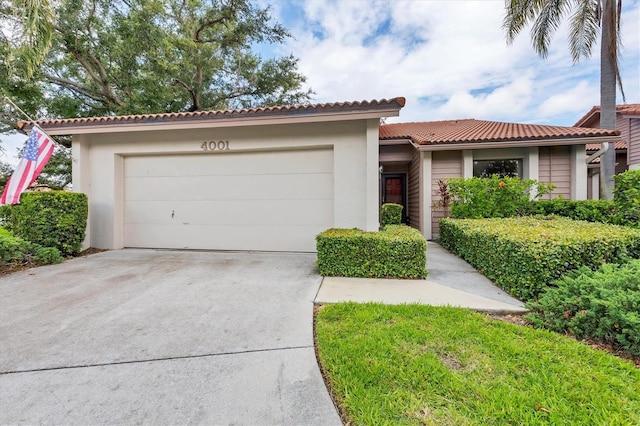 4001 Wilshire Cir E Unit 72, Sarasota, FL 34238 - view of front of home with a tile roof, concrete driveway, stucco siding, and an attached garage