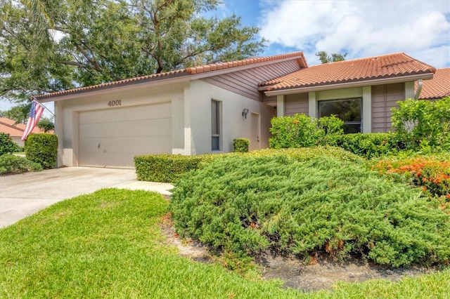 4001 Wilshire Cir E Unit 72, Sarasota, FL 34238 - view of front of house with a tile roof, driveway, a garage, and stucco siding
