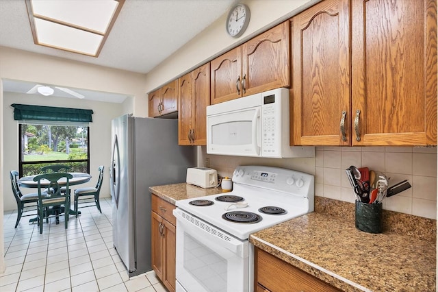4001 Wilshire Cir E Unit 72, Sarasota, FL 34238 - kitchen featuring white appliances, brown cabinetry, decorative backsplash, and light tile patterned flooring