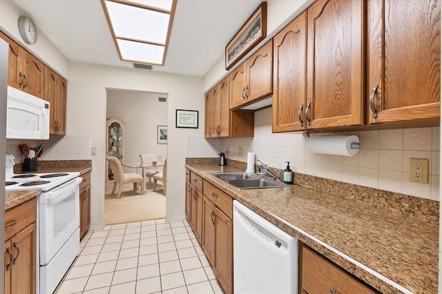 4001 Wilshire Cir E Unit 72, Sarasota, FL 34238 - kitchen with white appliances, brown cabinetry, backsplash, and light tile patterned floors