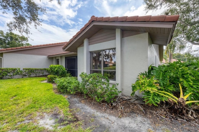 4001 Wilshire Cir E Unit 72, Sarasota, FL 34238 - view of side of property with a tile roof, stucco siding, and a lawn