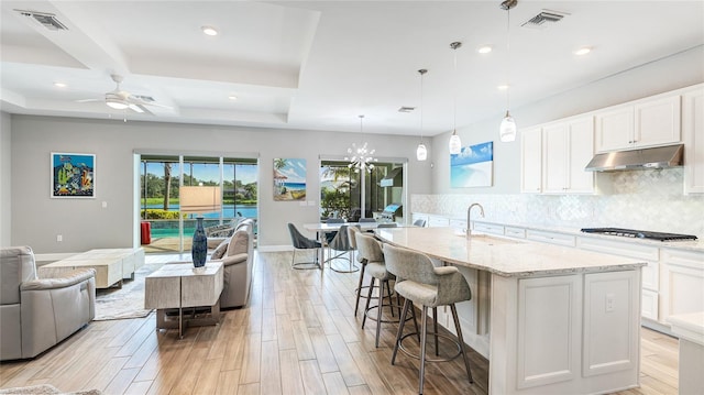 3431 Chestertown Loop, Bradenton, FL 34211 - kitchen featuring under cabinet range hood, open floor plan, stainless steel gas stovetop, light wood-type flooring, and recessed lighting