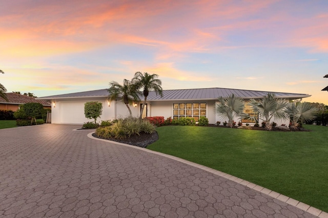 510 Putter Ln, Longboat Key, FL 34228 - view of front of home with decorative driveway, stucco siding, a garage, a yard, and a metal roof