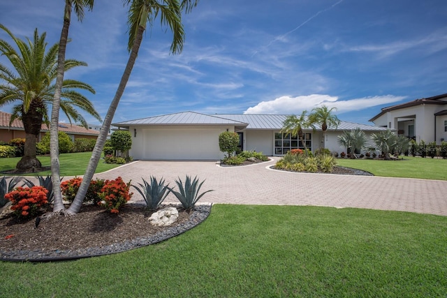 510 Putter Ln, Longboat Key, FL 34228 - view of front of property featuring decorative driveway, an attached garage, stucco siding, a front lawn, and a metal roof