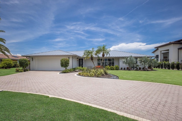 510 Putter Ln, Longboat Key, FL 34228 - view of front of property with decorative driveway, a garage, a metal roof, stucco siding, and a front lawn