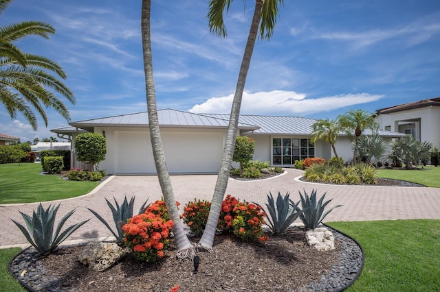 510 Putter Ln, Longboat Key, FL 34228 - view of front of house with stucco siding, decorative driveway, a front lawn, a garage, and a metal roof