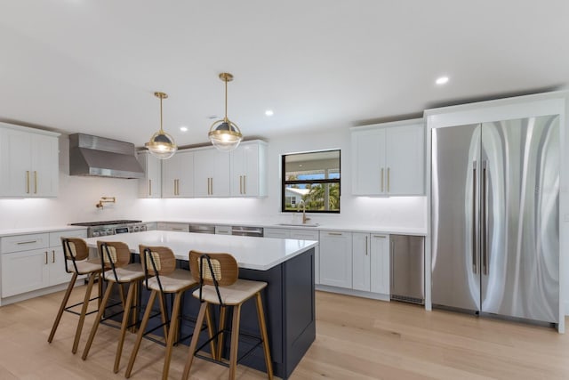 510 Putter Ln, Longboat Key, FL 34228 - kitchen featuring freestanding refrigerator, wall chimney exhaust hood, a kitchen bar, light countertops, and a kitchen island