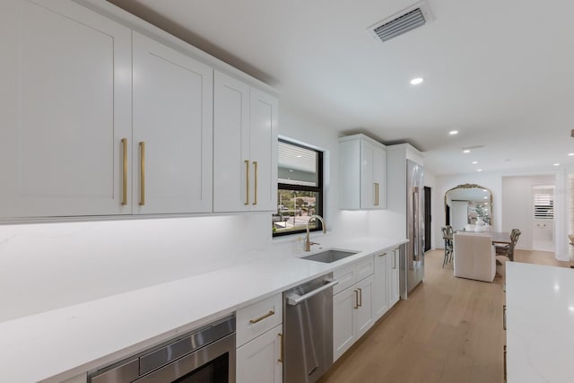 510 Putter Ln, Longboat Key, FL 34228 - kitchen with appliances with stainless steel finishes, white cabinetry, light wood finished floors, recessed lighting, and arched walkways