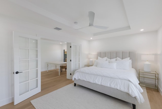 510 Putter Ln, Longboat Key, FL 34228 - bedroom featuring french doors, recessed lighting, light wood-style flooring, and a tray ceiling