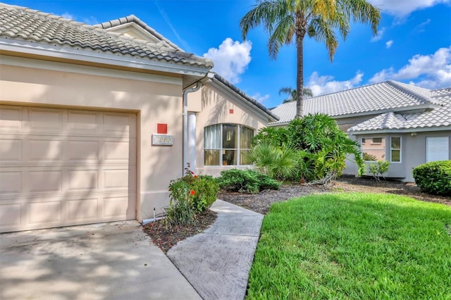 7960 Hampton Ct, University Park, FL 34201 - entrance to property with a tiled roof, an attached garage, stucco siding, and a lawn